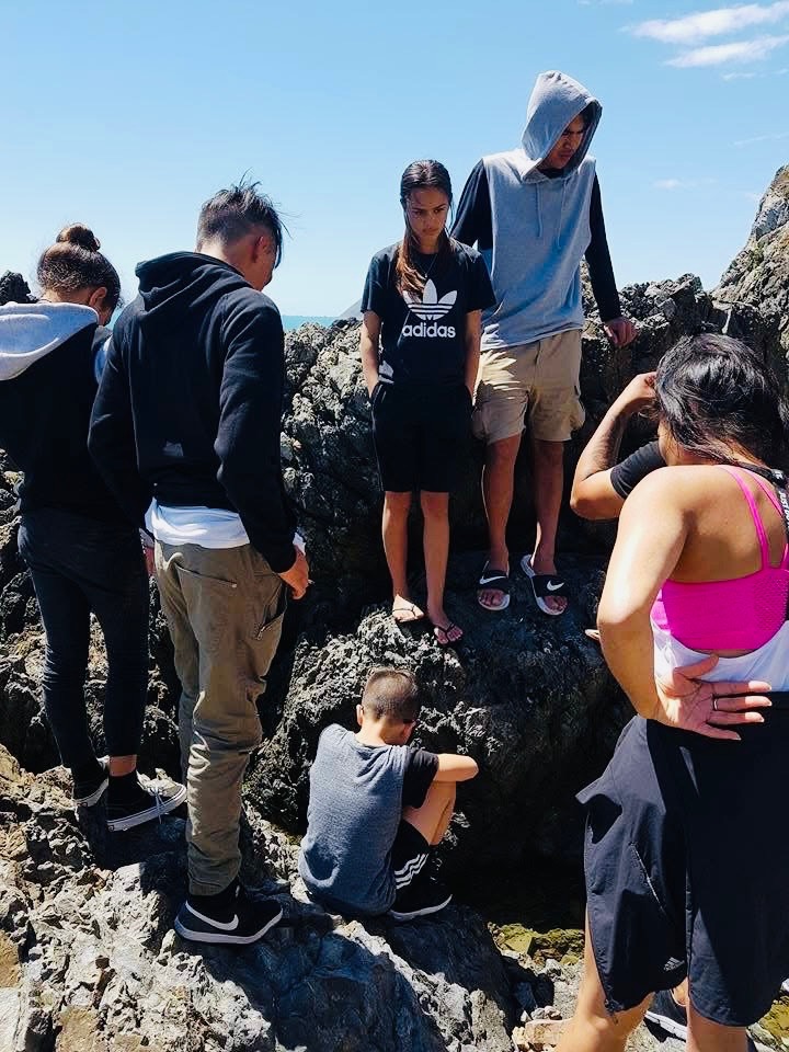 Group of people exploring coastal rocks together
