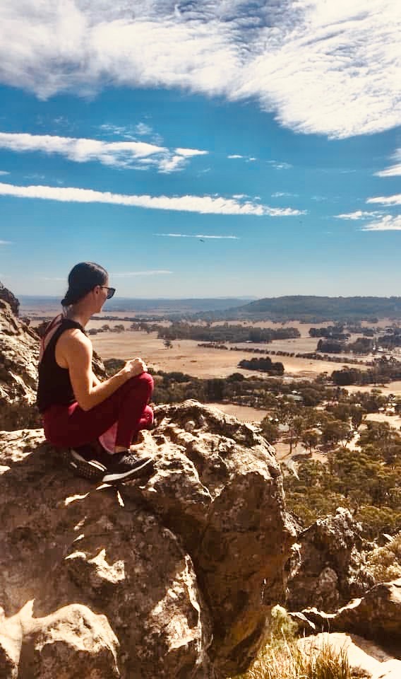 Person sitting on a clifftop looking over a valley